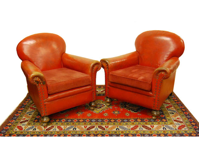 A pair of red leather-upholstered armchairs, early 20th Century