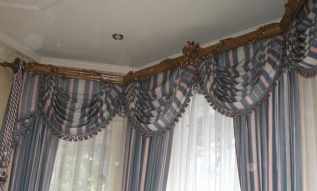 Two similar giltwood and gesso pelmets with blue and pink striped curtains