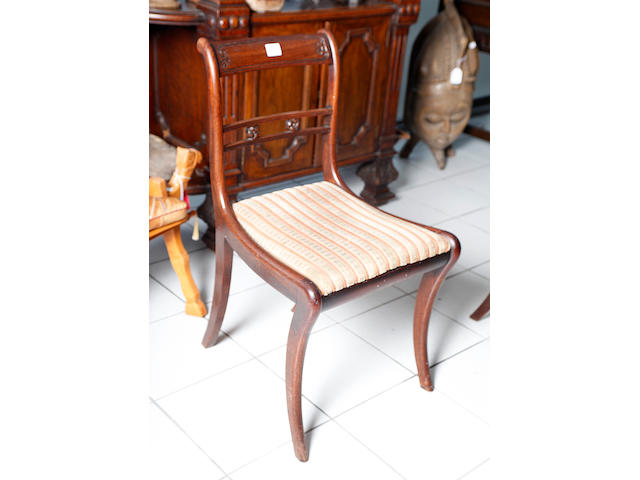 A set of six Regency mahogany dining chairs, with carved top rails and rosette carved bar backs, drop in seats, on sabre legs.