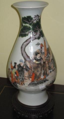 A Chinese porcelain vase, 20th Century, pear shape, painted in the famille palette with figures in a rocky landscape with pine trees, on a carved wooden stand, 44cm. (2)
