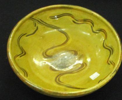 Michael Cardew at the Winchcombe pottery:  a shallow earthenware bowl, on an ochre glaze with a sgrafilto decoration, impressed marks, 28cm.