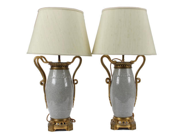 A pair of Chinese crackleglaze barrel shape vases, later gilt metal mounted as table lamps, having dual entwined snake side handles, the pierced socles with outset foliate cast square section feet, 44cm.
