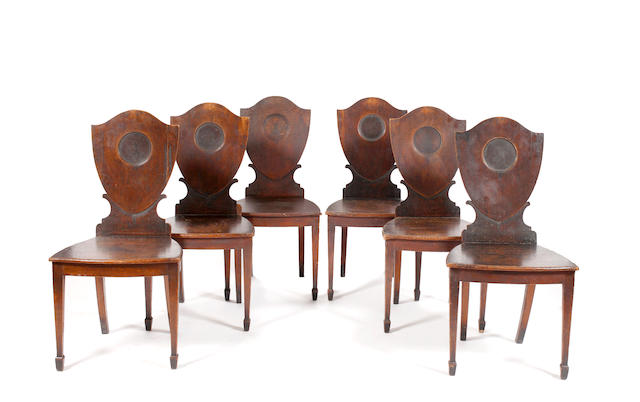 A set of six late George III oak shield back hall chairs