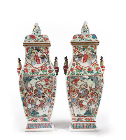 A large pair of Canton famille rose vases and cover, 19th Century, each of baluster form, enamelled on each of the main sides with a rectangular panel enclosing figures engaged in combat or within a court setting, all with similar shaped cartouches to the necks, all amidst birds and butterflies, amidst melon and peach sprigs each blossoming peony and leaves, inset to each side with moulded handles in the form of ladies seated on lotus, the covers surmounted by finials in the form of seated ladies, 55.5cm high. (4)