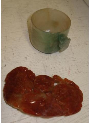 A mottled jadeite cup, the handle carved as a bat, 4cm, high, together with a mottled jade belt buckle carved with two Buddhistic lions with a ball. (2)