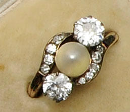 A diamond and pearl three stone ring of crossover design