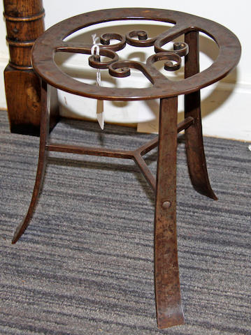 An Arts and Crafts style wrought iron trivet,on splay legs and a yew wood low stool, on four bobbin turned legs (one replaced) (2)