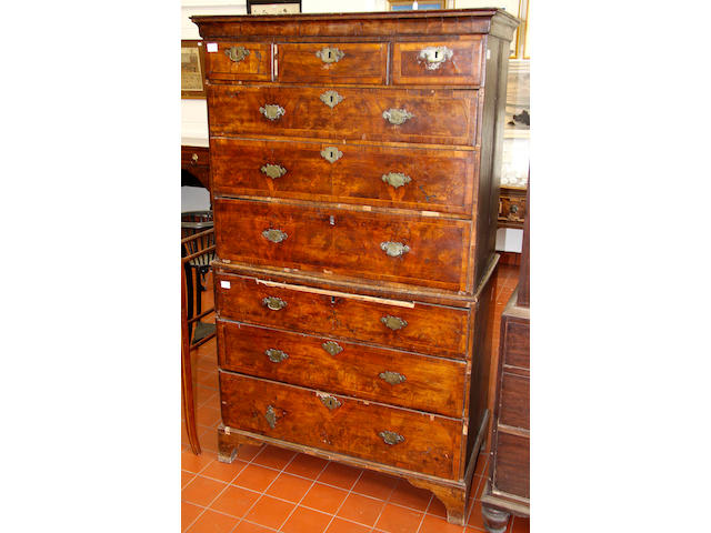 An early George II walnut tallboy,with ogee cornice, crossbanded and feather banded drawers, original engraved handles (some bows lacking), the side in unveneered oak, distressed, 105cm wide178cm high, (41" wide70" high)