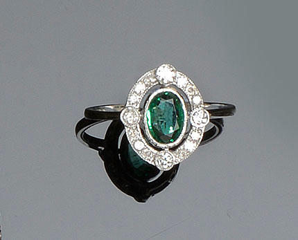 An emerald and diamond oval cluster ring