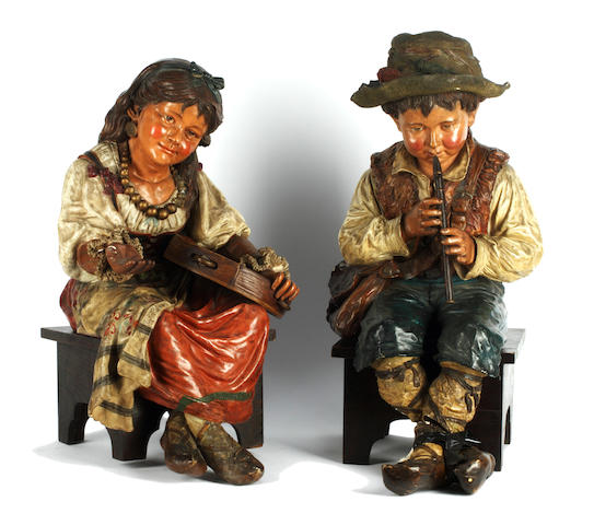 A pair of Neapolitan polychrome decorated terracotta figures of a seated boy and girl