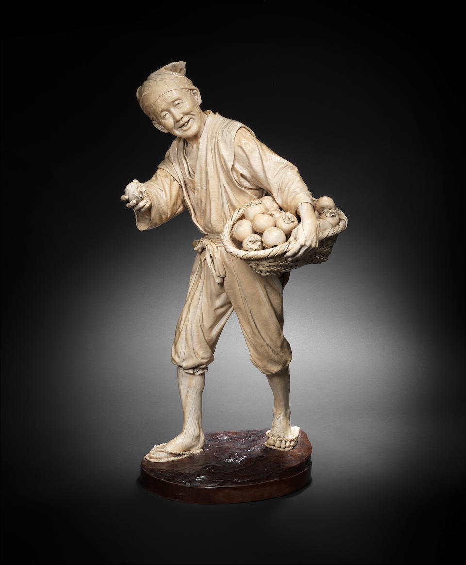 A fine and exceptionally tall ivory okimono figure of a fruit seller Meiji Period