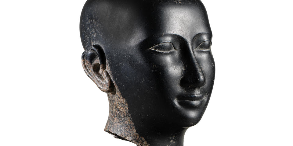 An Egyptian granite head of a priest
