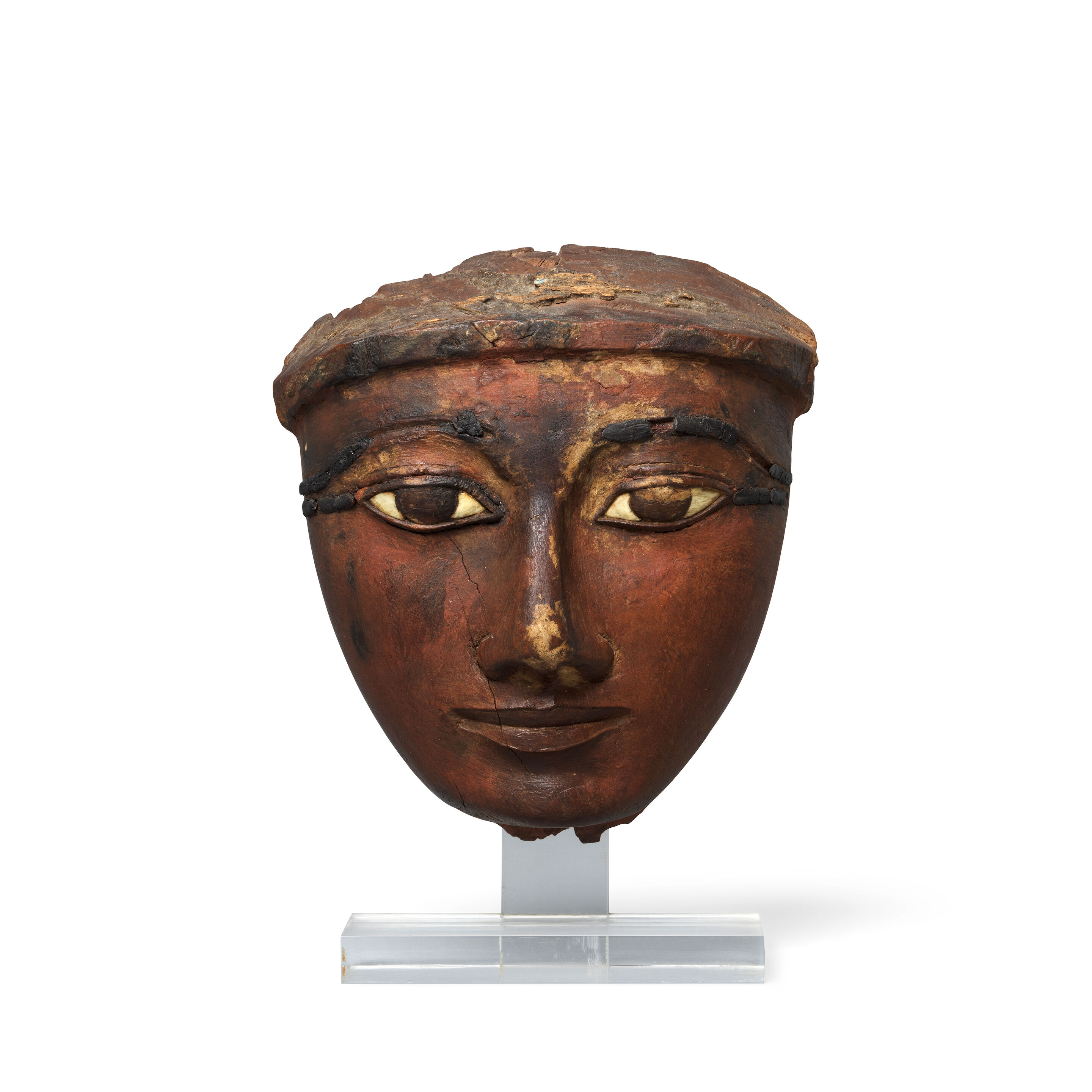 An Egyptian wood mask with inlaid eyes