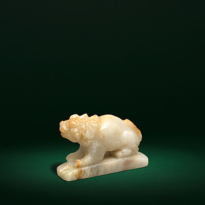 A RARE PALE GREEN AND RUSSET JADE CARVING OF A LION Tang/Liao Dynasty