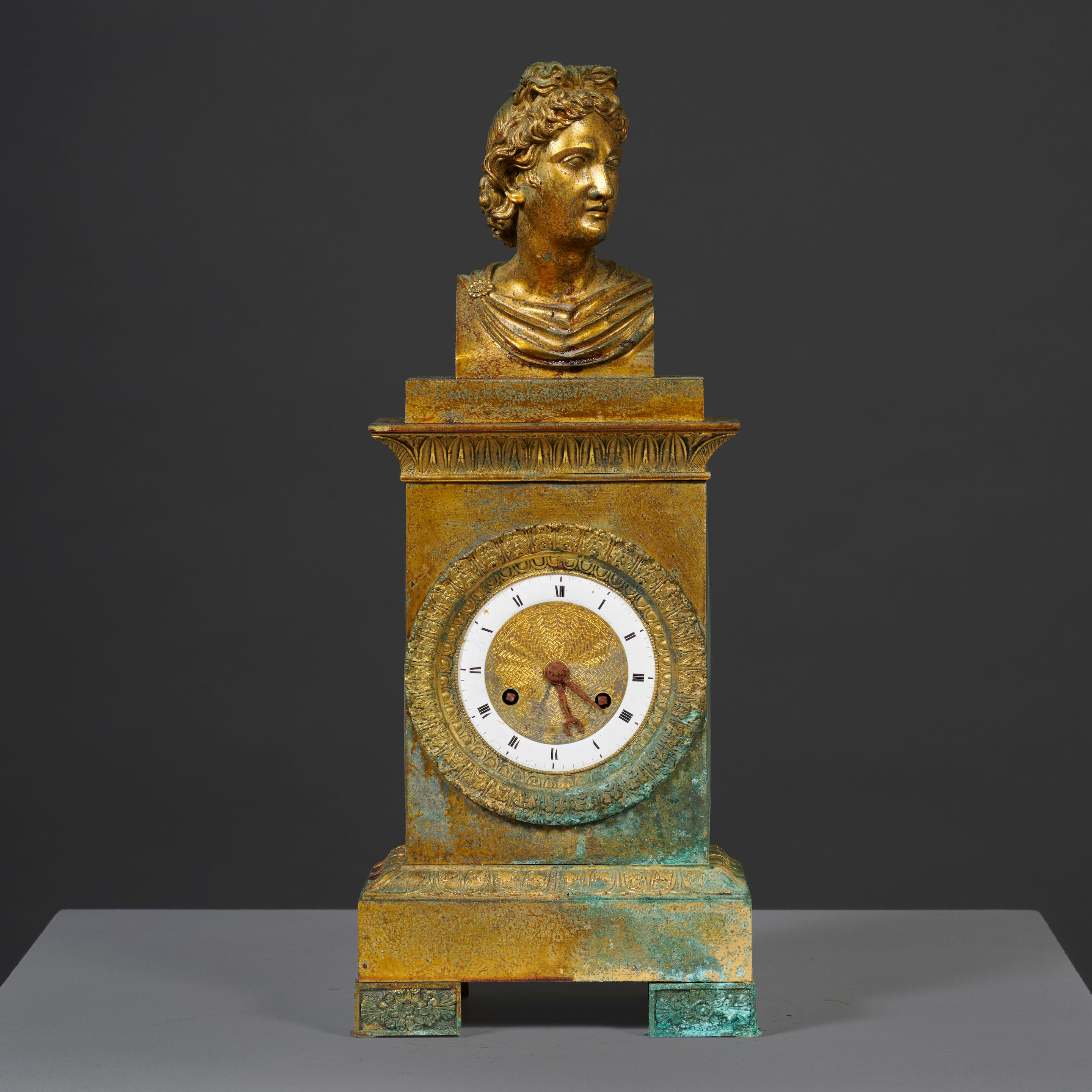 Pendule borne surmontée du buste de l'Apollon du Belvédère en bronze doré et ciselé d'époque Restauration A mantel clock surmounted by the bust of the Apollo Belvedere in gilt-bronze, first half of the 19th century