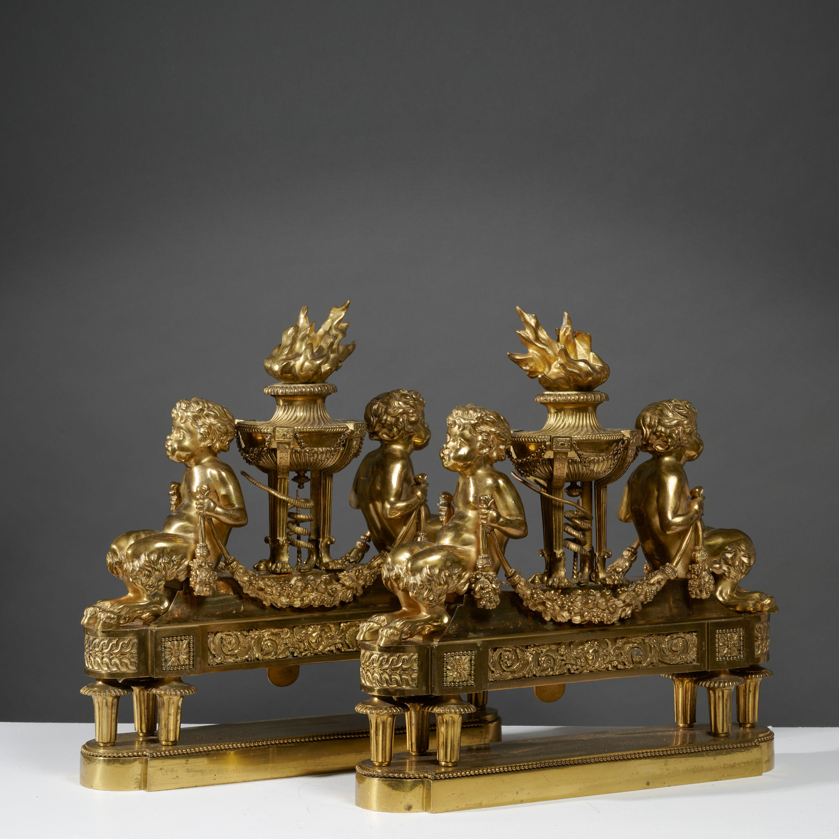 Paire de chenets en bronze doré figurant deux enfants encadrant une athénienne enflammée du XIXe siècle A pair of 19th century gilt-bronze chenets depicting two children flanking a flaming athénienne